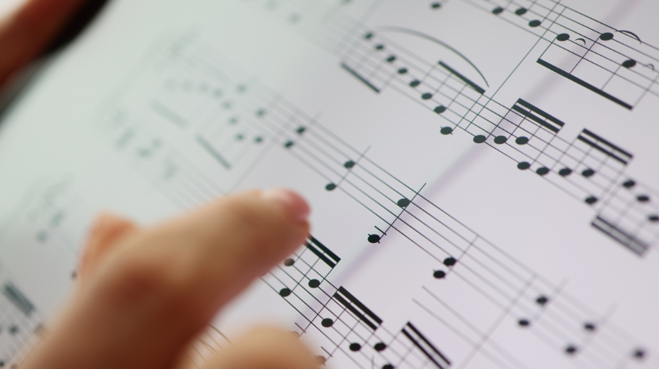 A finger runs across notes on a page of sheet music.
