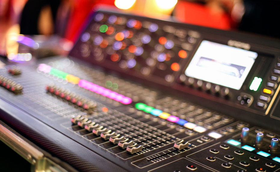 A mixing console with sliders, colored lights and a bright screen.